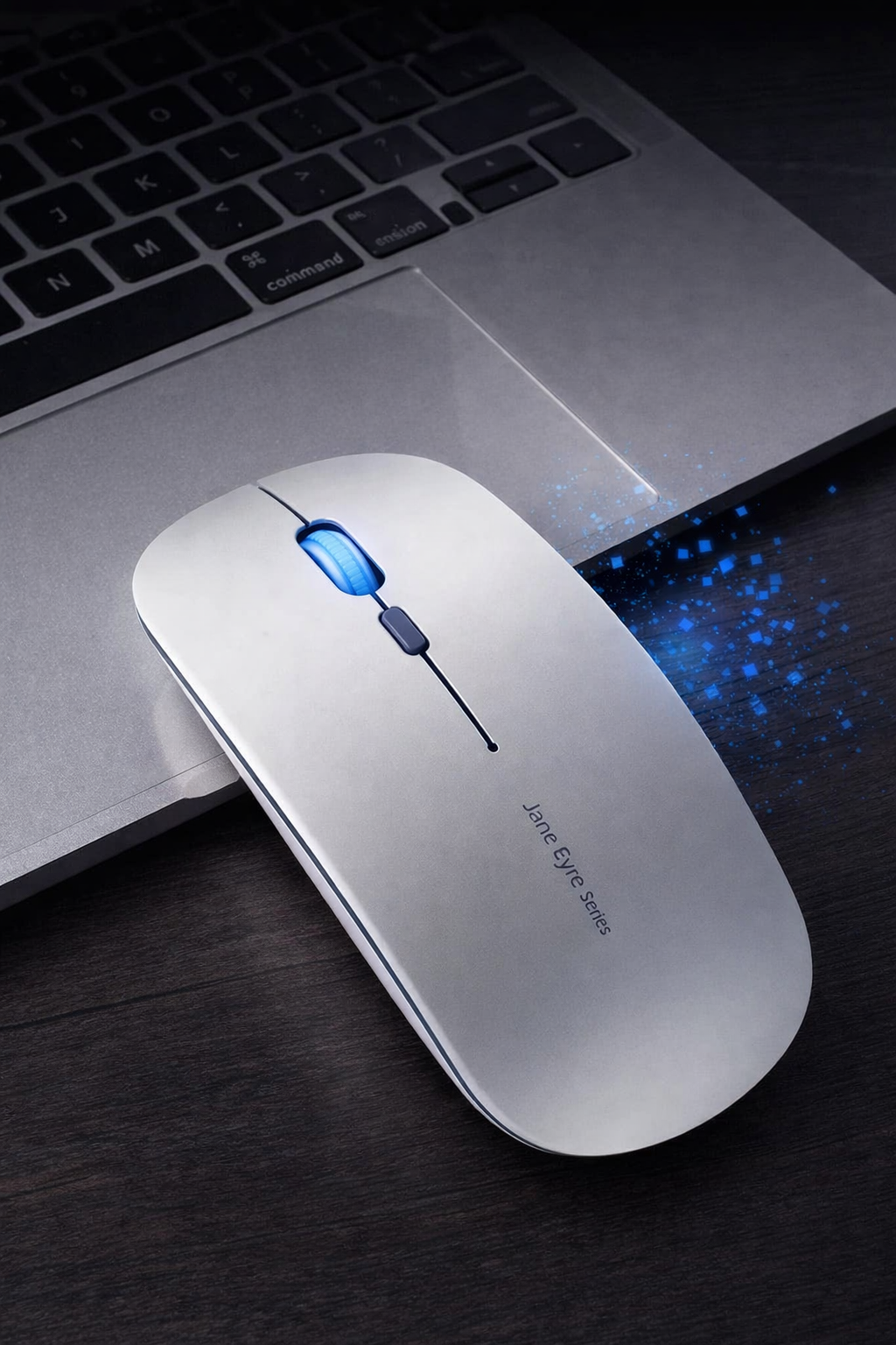 White computer mouse with blue light on a dark surface next to a laptop